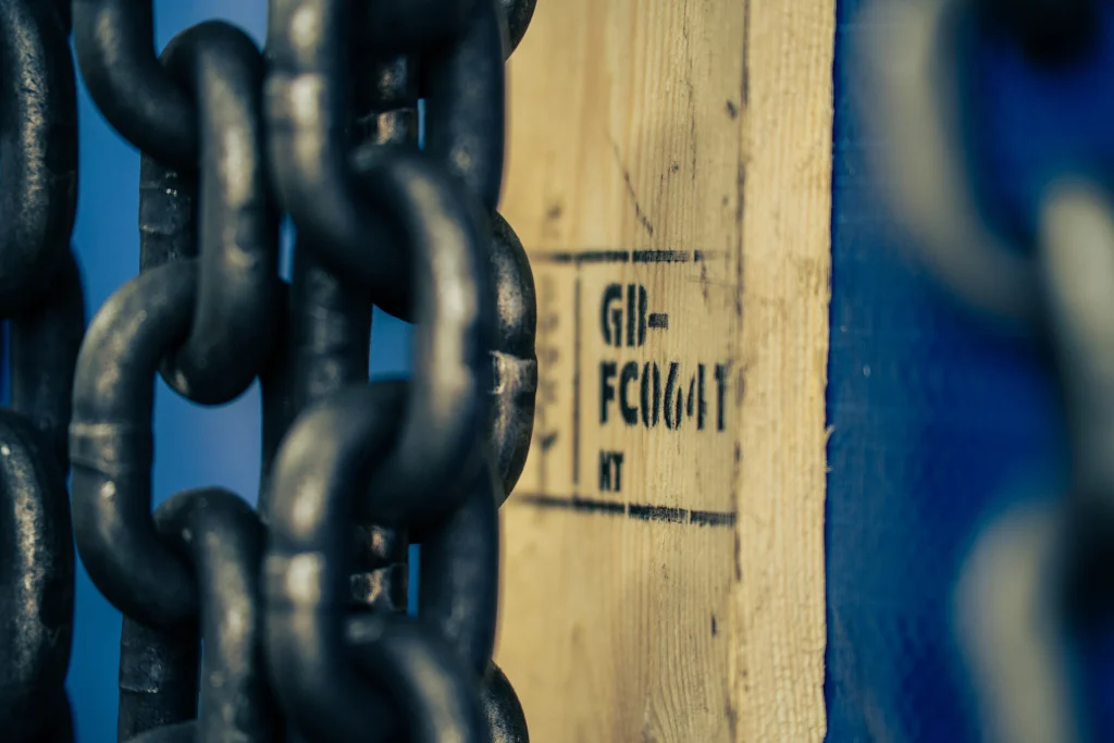Close-up of ISPM 15 timber marking and heavy-duty chain securing an export case