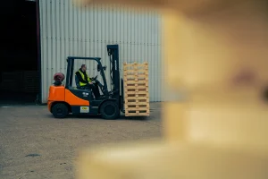 Forklift moving softwood pallets and skids at IM Export Services facility.
